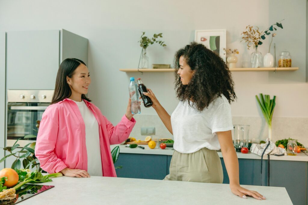 Two women sharing a lighthearted moment in the kitchen, fresh groceries on the counter